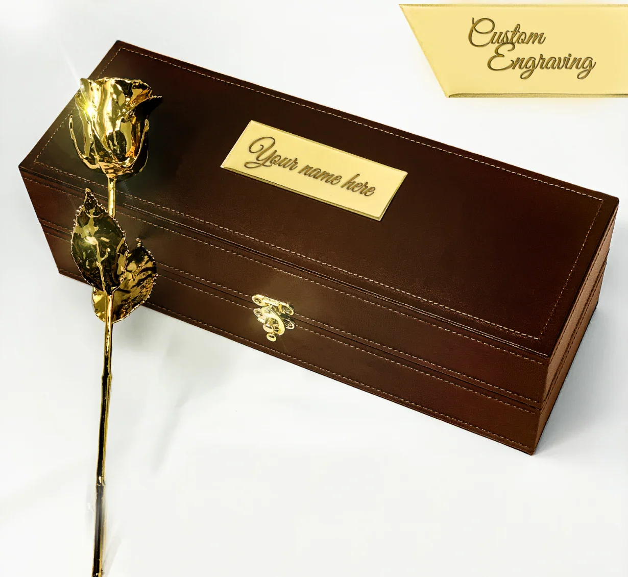 A real 24K gold-dipped rose displayed beside a brown leather custom-engraved gift box with a gold nameplate, part of LovePicker’s Engraved Gift Boxes collection.