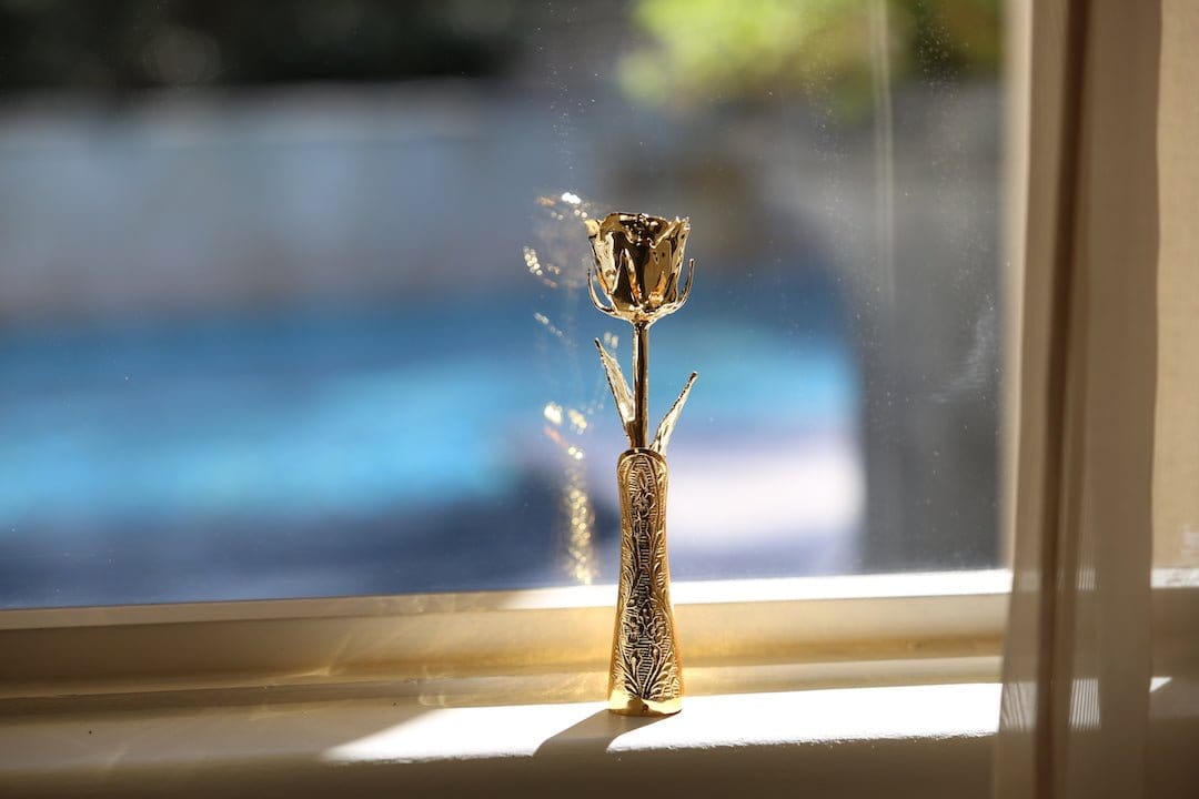 Lovepicker gold dipped vase shaped as a 24k gold rose vase holder on a windowsill with natural light