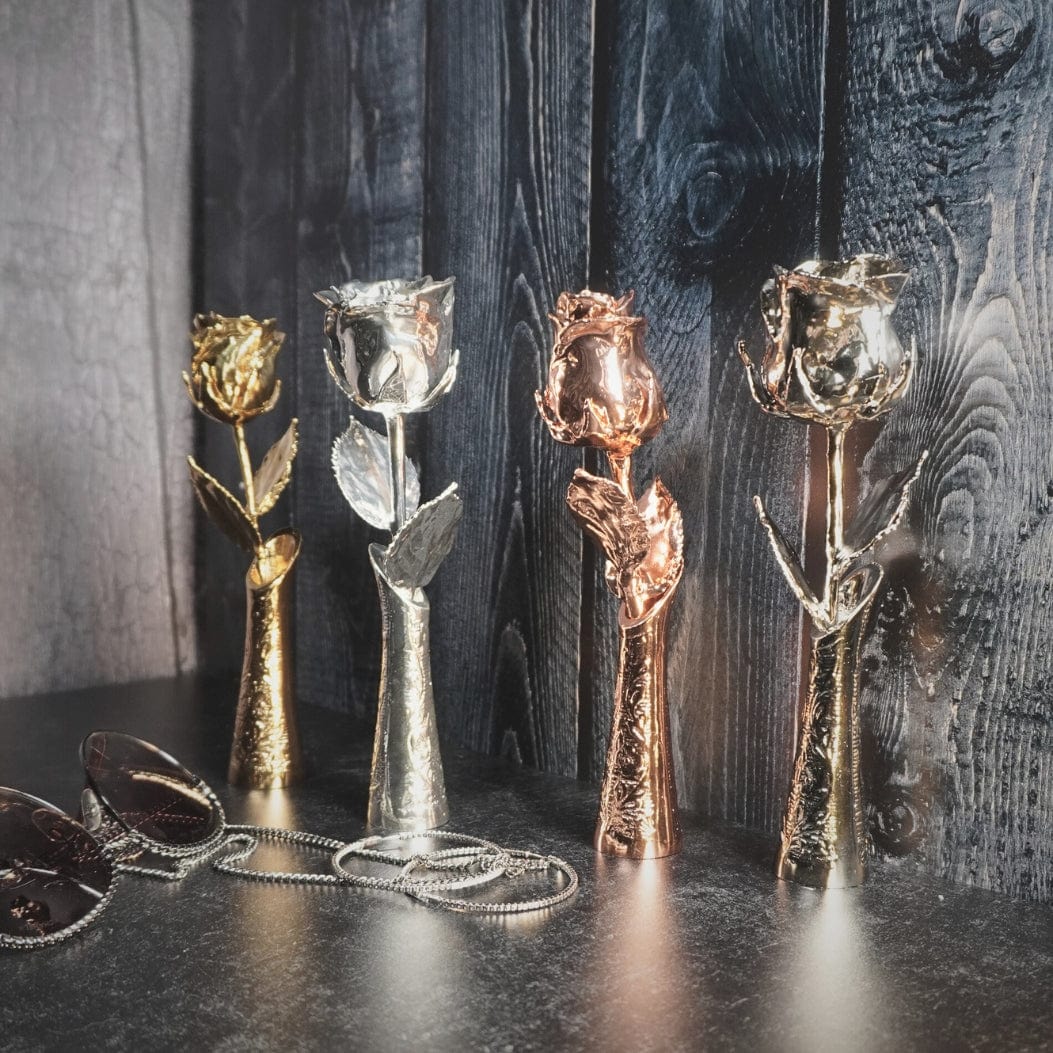 Five real preserved roses dipped in 24K gold, silver, and rose gold finishes, standing upright against a dark wooden background from the LovePicker luxury collection.