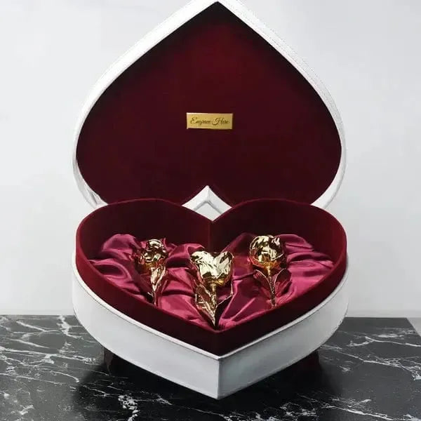 Heart-shaped box with gold rose sculptures on a marble surface