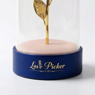 Gold 'Love Picker' glass dome on a beige cushion with a blue base against a white background
