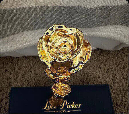 Gold rose-shaped object with 'Love Picker' branding on a textured surface