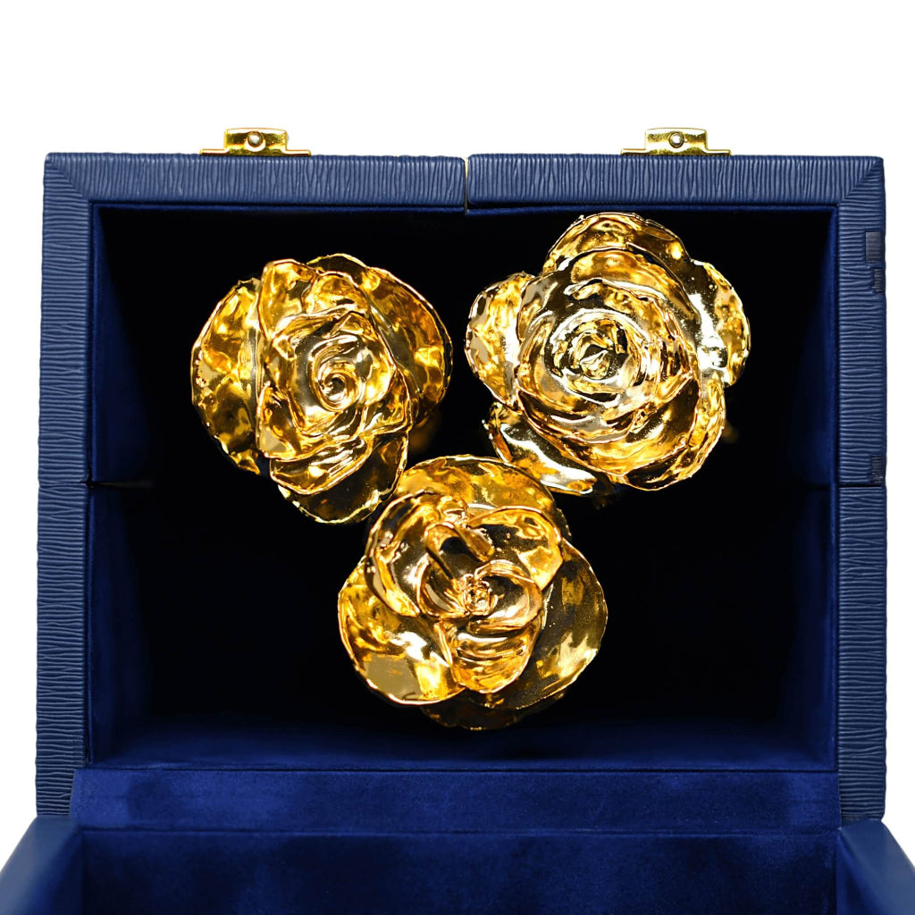 Three gold roses in a blue box on a white background