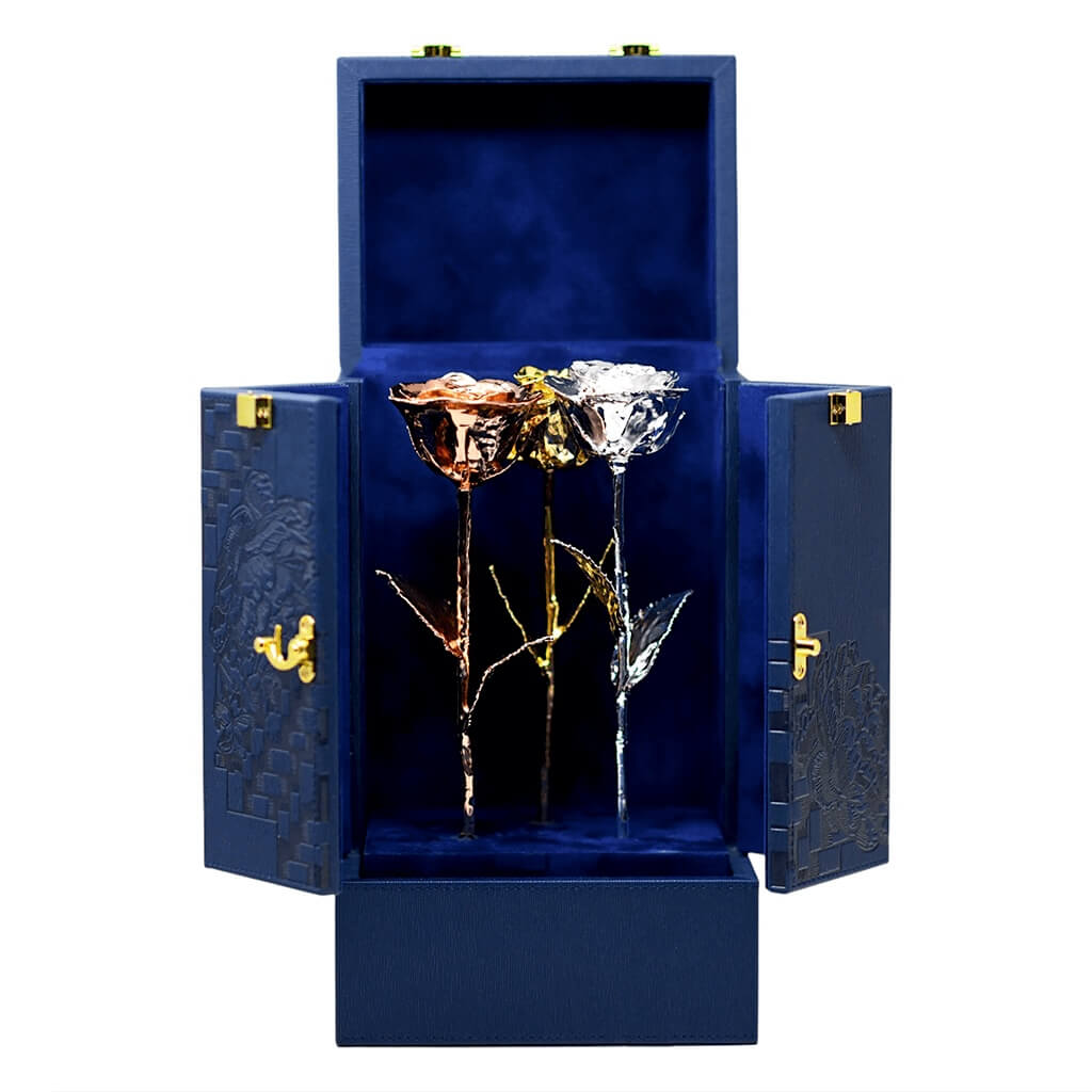 Two gold and silver roses in a blue decorative box on a white background