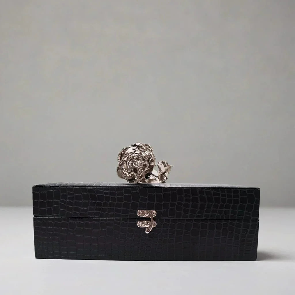 Black crocodile-leather gift box with a  platinum rose on a light gray background