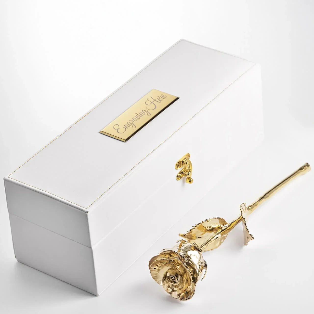 Gold rose next to a white box with a gold tag on a light gray background